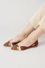 Bailarinas planas confeccionadas artesanalmente con una combinación de ante, napa y tejido estampado. Presentan un diseño geométrico con tiras entrelazadas en la parte delantera que combinan tonos vino tinto, beige, naranja teja, marrón y estampado de leopardo. Cuentan con un ligero tacón y plantilla fija de piel.