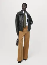 Pantalón wide leg de tiro bajo confeccionado en tejido de pana color tostado, con bolsillos laterales y bolsillos de ribete en la parte posterior.