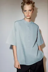 Camisa de manga corta y corte evasé confeccionada en hilatura con mezcla de algodón. Presenta cuello redondo mao y cierre frontal parcial con botones.