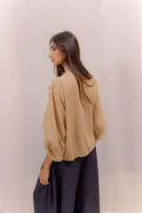 Camisa blanca de algodón con escote en V, volados delanteros con detalles de encaje y mangas largas con puños fruncidos.