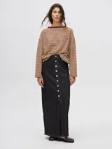 Pollera midi de denim color marrón, de tiro medio y corte recto. Presenta cierre frontal con botones metálicos a la vista y un tajo central en el ruedo con terminación deshilachada.