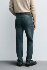 Pantalón de jean corte slim fit, color gris con efecto lavado. Presenta diseño de cinco bolsillos, cierre frontal con cremallera y botón, y tejido elástico.