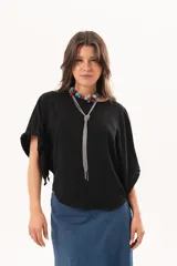 Blusa de silueta relajada y caída fluida, color negro, con escote redondo y mangas amplias.