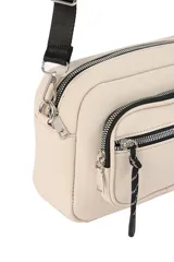 Bandolera de diseño compacto en color beige, con compartimento principal y bolsillo frontal, ambos con cierre. Incluye correa larga regulable y detalle de tirador con cordón en el cierre frontal.