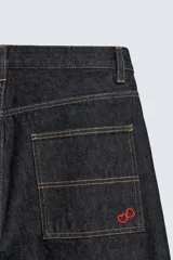 Pantalón chino de denim de algodón rígido, color índigo oscuro sin lavar. Corte baggy fit, tiro medio, con bolsillos frontales y traseros de plastrón. Presenta bordados a contraste en la cintura y en el bolsillo trasero.