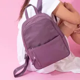 Mochila roja de nylon resistente con detalle en simil cuero. Tiene cierre principal, bolsillo frontal, bolsillo trasero con cierre y bolsillos laterales. Las correas son a tono.