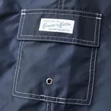 Short de baño azul marino Katin modelo Waterman, con costuras a contratono en blanco, cordón de ajuste en la cintura y un parche estampado en la pierna izquierda.