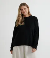 Suéter de punto texturizado con cuello redondo y mangas largas con sisa caída. Presenta un diseño liso y holgado, ideal para un estilo casual y versátil.