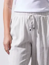 Pantalón de lino color beige con rayas verticales blancas, pretina elastizada con cordón ajustable, bolsillos laterales y ruedo con botamanga.