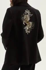 Blazer negro de corte clásico con cierre frontal de botones y detalle de bordado artístico en la espalda que representa un caballo y motivos florales.