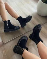 Botas cortas de cuero vacuno color negro, con diseño combinado de gamuza y cuero texturizado con efecto reptil en el talón. Presentan cierre lateral metálico, puntera reforzada y suela track dentada con costura visible.
