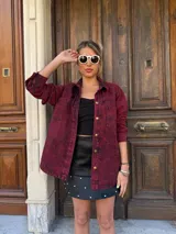 Camisa de denim color borgoña con efecto lavado, corte holgado, cuello clásico y cierre frontal con botones dorados.