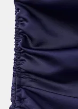 Vestido midi asimétrico de un solo hombro, color azul marino, confeccionado en satén con fruncido lateral, tajo discreto en el lateral de la falda y diseño entallado.