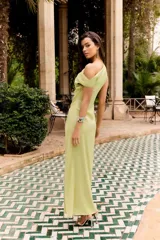 Vestido largo verde lima de un solo hombro con detalle drapeado, hebilla decorativa en la cintura y tajo frontal profundo.