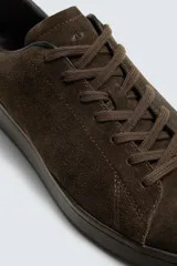 Zapatilla de cordones confeccionada en piel con acabado de serraje, de horma redonda y suela a tono.