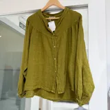 Camisa de lino color verde pistacho, con cuello mao y cierre frontal de botones. Presenta mangas largas abullonadas con puños elásticos y corte holgado.