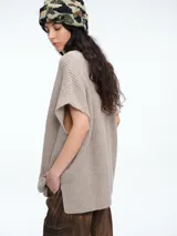 Chaleco tipo poncho de tejido de punto color tostado, con cuello polera y diseño holgado con laterales abiertos.