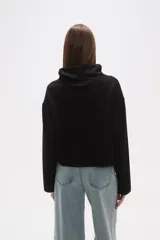 Buzo de cuello alto tipo polera, color verde oliva, con corte holgado, mangas largas y un bolsillo frontal aplicado en el pecho.