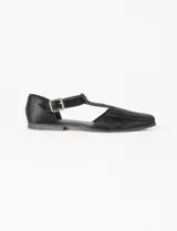 Zapato guillermina de cuero con pelo negro, con punta cuadrada, tira sobre el empeine con hebilla metálica y suela plana.
