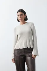 Top de tejido acanalado con sutil acabado metalizado, de silueta entallada con diseño peplum en la cintura y mangas largas levemente acampanadas.