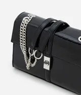 Cartera tipo shoulder bag de tamaño mediano, confeccionada en poliuretano con textura efecto croco. Presenta una tapa frontal con cierre metálico de giro, asa de mano reforzada y una correa larga de cadena plateada. Diseño estructurado con acabado sofisticado.