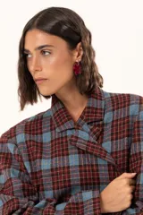 Blazer de corte oversize con estampado de cuadros en tonos azul, bordó y marrón. Presenta solapas clásicas, bolsillos con solapa en el frente y cierre frontal con botones.