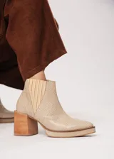 Botín de cuero color beige con textura reptil, elástico lateral y cierre interno. Tiene plataforma delantera y taco de madera.