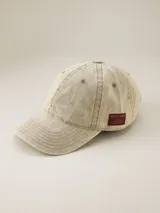 Gorra de seis paneles marca Benson & Thomas con visera curva y efecto de tela lavada. Presenta una etiqueta lateral bordó con el logo de la marca.