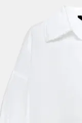 Camisa blanca de la colección ZARA Woman, confeccionada en hilatura con lino, con escote en pico, manga larga con puño ancho y detalles desflecados en cuello y bajo.