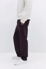 Jogger color bordó en tejido suave de mezcla de algodón, con pliegue cosido en la parte delantera. Presenta cintura elástica con cordón ajustable, bolsillos laterales y un bolsillo insertado en la parte trasera.