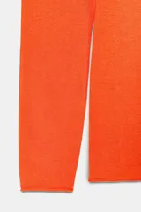 Jersey de punto fino color naranja, con cuello redondo y manga larga.