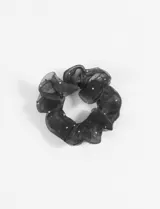 Gomita de pelo tipo scrunchie color negro, de poliéster y con brillos plateados.
