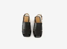 Sandalias de cuero negro con tiras anchas entrecruzadas, punta cuadrada, talón abierto con pulsera ajustable y hebilla metálica, y taco ancho medio.