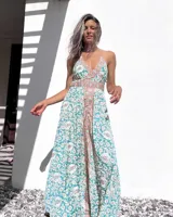 Vestido largo de tirantes con estampado floral en tonos celeste, blanco y rosa. Tiene escote halter y espalda descubierta con lazos.