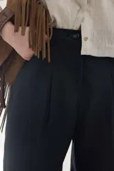Pantalón de lino marrón de tiro medio, con calce holgado y diseño de piernas amplias. Cuenta con bolsillos traseros, trabillas para cinto y un pin bordado en contraste.