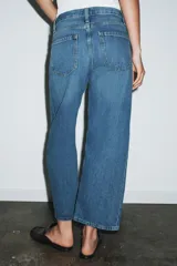 Jeans de tiro medio con corte relajado y largo al tobillo. Presenta diseño de cinco bolsillos, trabillas en la cintura y cierre frontal con cremallera y botón metálico.