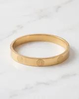 Esclava rígida de acero con baño de oro, diseño de superficie lisa con grabados circulares del símbolo de San Benito.