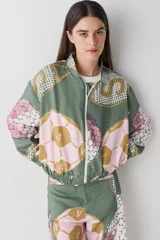 Campera bomber de corte holgado con cierre frontal, confeccionada en tela con estampado gráfico de pelotas de fútbol y redes en tonos verdes, rosados y ocres.