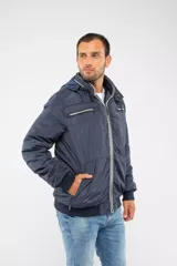 Campera de nylon color azul marino con cierre frontal completo, capucha desmontable y puños elásticos. Presenta bolsillos con cierre y logo aplicado en la manga.