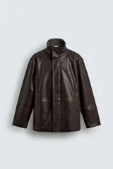 Cazadora de corte relajado confeccionada en tejido efecto piel color marrón oscuro. Presenta cuello subido con interior forrado en tejido de cuadros, manga larga, bolsillos de vivo en la cadera y cierre frontal con cremallera oculta por solapa con botones a presión.