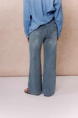 Pantalón de jean con tiro alto y corte wide leg, de color azul con efecto desgastado. Cuenta con cierre y botón frontal, además de bolsillos funcionales.