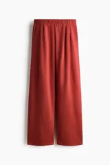Pantalón de punto pesado color terracota, de corte amplio y pernera recta. Cuenta con cintura elástica revestida y pliegues frontales.