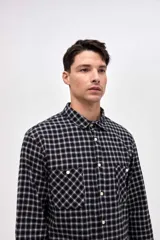 Camisa de corte regular fit confeccionada en algodón, con estampado de cuadros, cuello solapa clásico, cierre frontal con botones y dos bolsillos en el pecho.