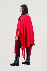 Poncho rojo de tejido artesanal con aplique central de crochet en forma de mandala con tonos amarillos, blancos y rojos. Presenta terminación con flecos en los laterales y diseño holgado.