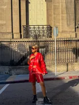 Bermuda de tiro alto en color rojo, confeccionada en cuero sintético, con costuras a la vista en contraste, cierre frontal y bolsillos laterales.