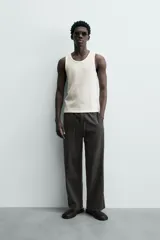 Pantalón de corte regular fit confeccionado en mezcla de algodón y lino. Presenta cintura elástica con cordón ajustable, cierre frontal con cremallera y botón, bolsillos laterales y bolsillo trasero de vivo con botón.