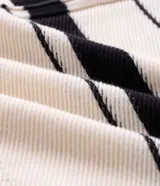 Suéter de punto Marfinno, color blanco y negro con diseño de rayas horizontales bicolor. Cuenta con cuello polo, cierre frontal completo y bolsillos laterales.