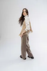 Chaleco negro de estilo boho, confeccionado en semigamuza con detalles de tejido de punto en el frente y la espalda. Presenta un diseño sin mangas con flecos en el ruedo, aportando movimiento y textura a la prenda.