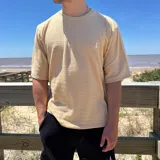 Remera color beige de tejido texturizado con logo bordado en el pecho.