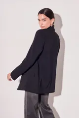 Blazer negro de corte clásico con solapas y mangas largas con puños con rayas verticales.